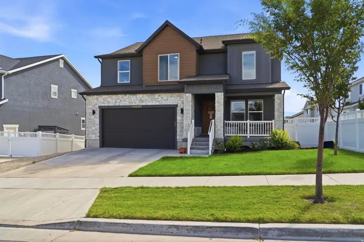 Contemporary exterior featuring stone accents, a covered porch with white railings, a two-car garage, and a concrete driveway