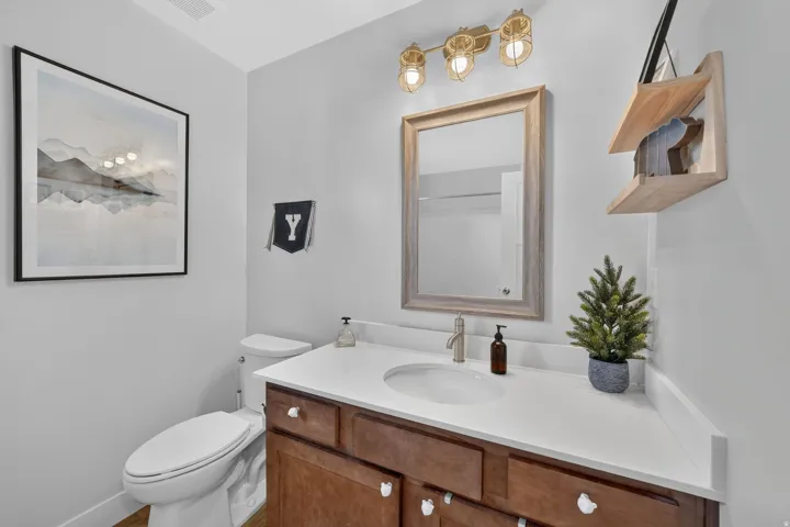 Vanity with wood-finish cabinetry, white countertop, and integrated sink
