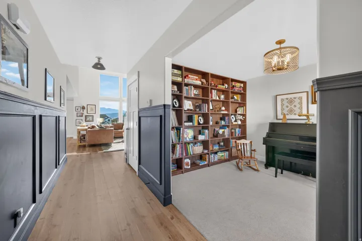 Wood-finish flooring, wainscoting details, built-in shelving, a full-height window, and a decorative ceiling fixture