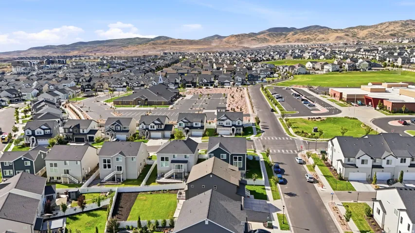 Expansive residential community featuring a variety of detached homes and townhomes, extensive green spaces, and mountain backdrop