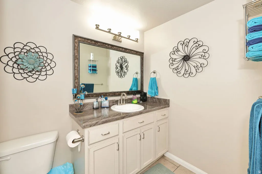 Vanity with integrated sink, framed mirror, wall-mounted light fixture, and floor tile