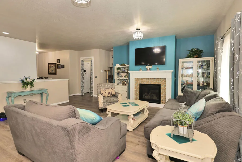 Living area featuring wood-finish flooring, a fireplace with a decorative tile surround and white mantel, and a half wall