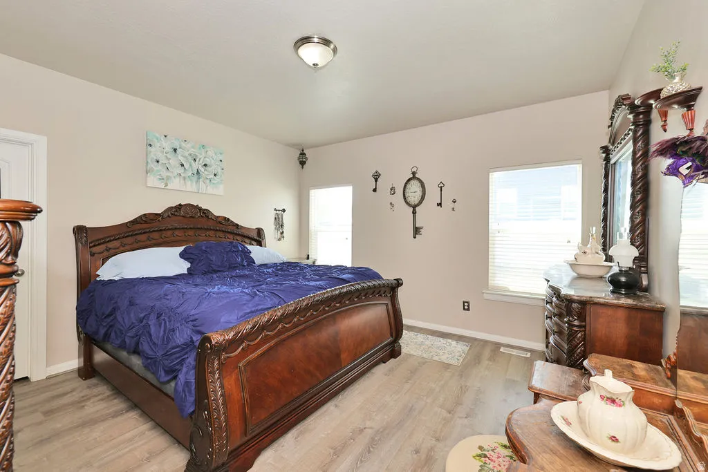 Pale neutral wall paint, wood-finish flooring, two windows with blinds, and a flush mount ceiling light