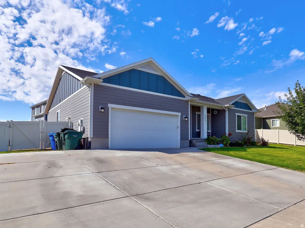 Gray siding exterior with blue accent gables, an attached two-car garage, concrete driveway, and a front lawn
