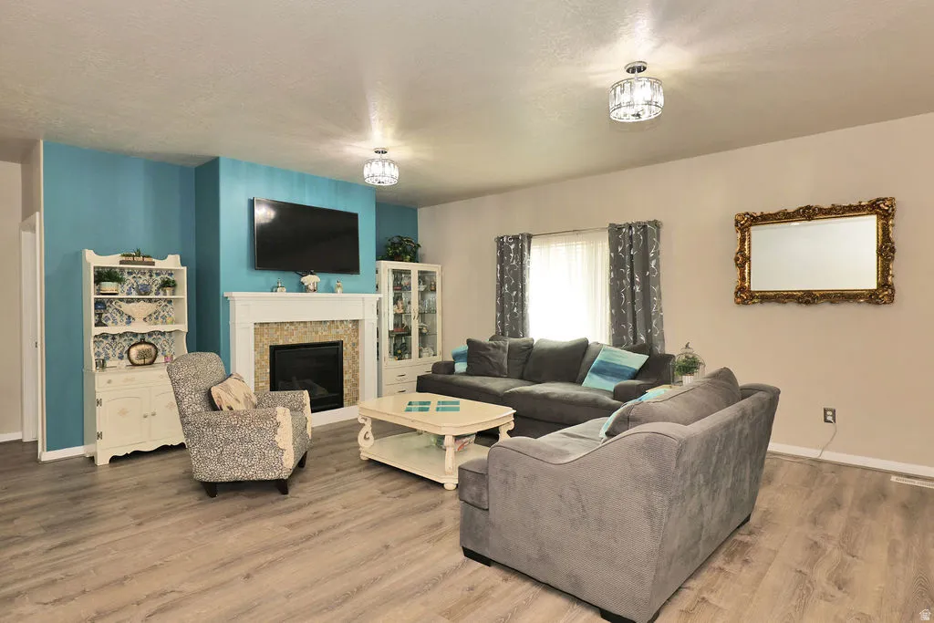 Living area featuring a fireplace with a white mantel and stone surround, wood-finish flooring, and recessed lighting