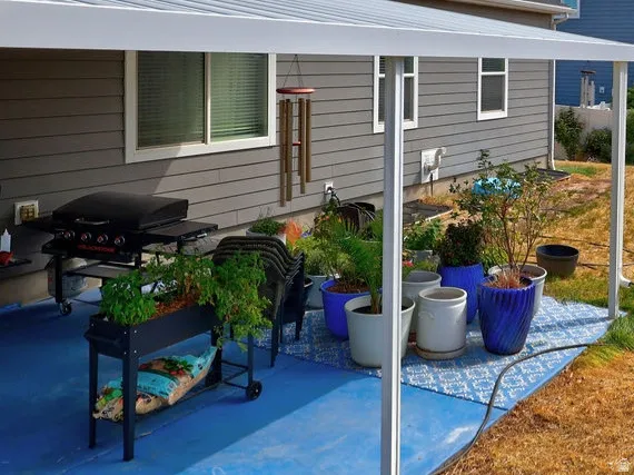 Covered patio with a painted concrete surface, adjacent to a sloped yard