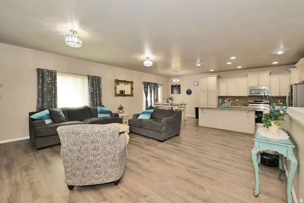 Open-concept living space featuring wood-finish flooring, recessed lighting, and chandelier light fixtures