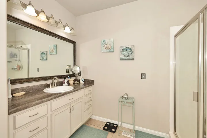 Vanity with an integrated sink, wood-finish countertop, white cabinetry, and brushed nickel hardware