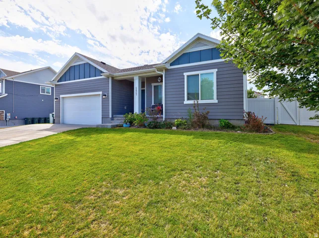 Siding exterior with contrasting gables, attached garage, covered front porch, and white perimeter fencing
