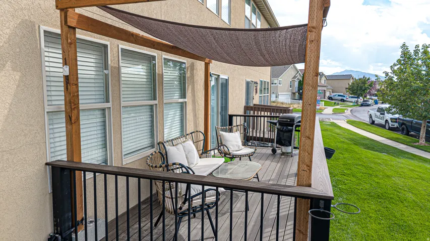 Composite deck with black metal railing and integrated seating area, topped with a wooden pergola featuring a retractable shade canopy