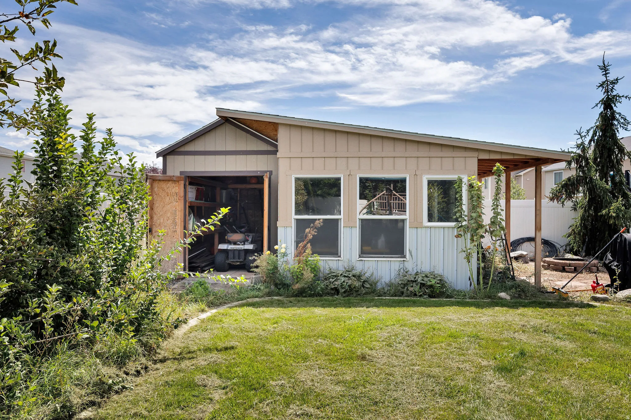 Shed with a single-slope roof, multiple windows, and covered exterior storage