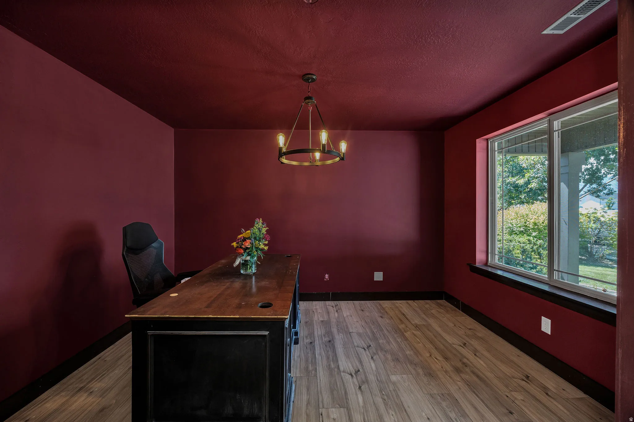 Room featuring wood-finish flooring, a contemporary chandelier, and a large window