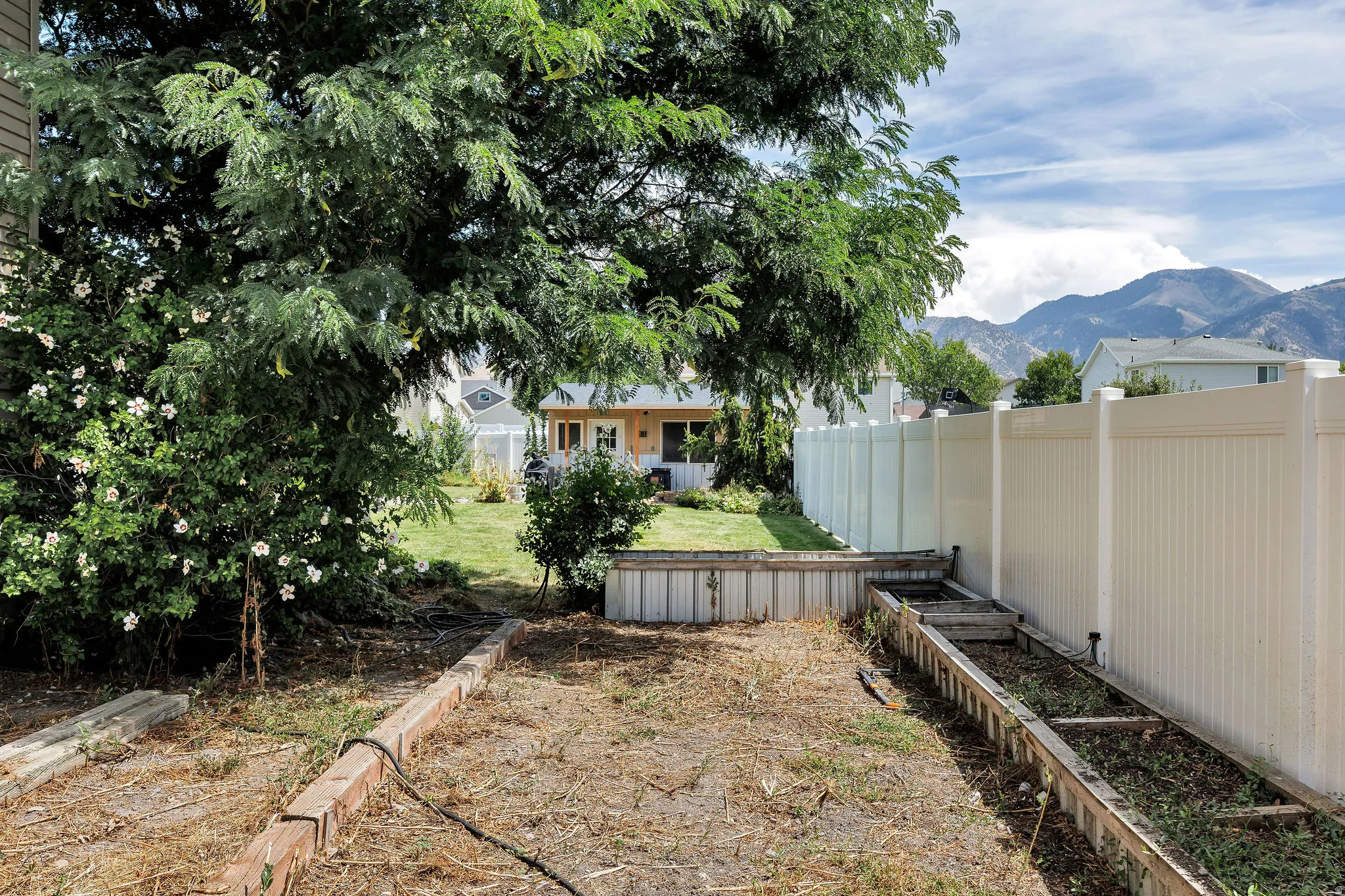 Backyard space featuring a privacy fence, established trees, and raised garden beds