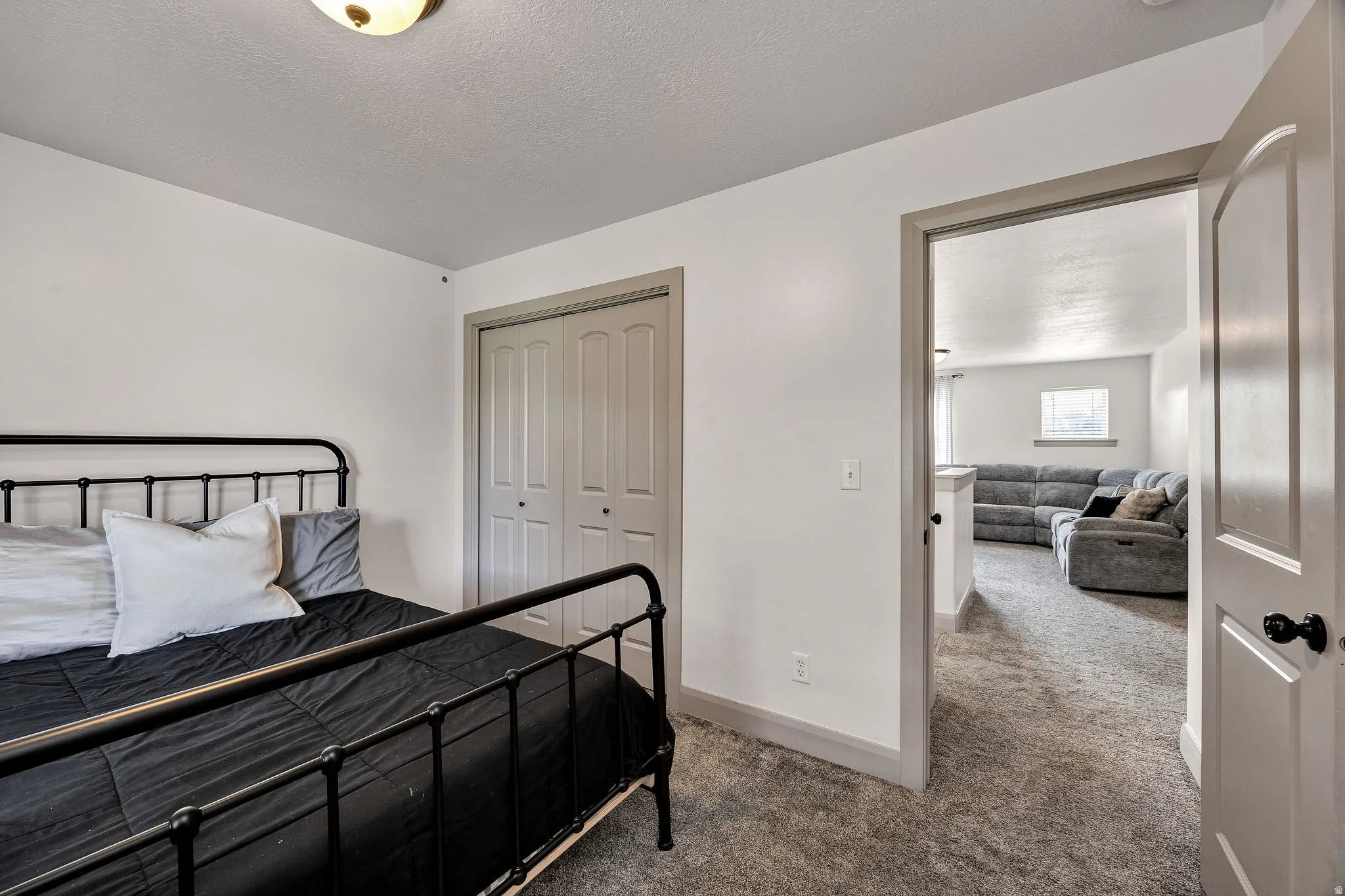 Bedroom featuring white walls, gray trim, textured carpet, and bi-fold closet doors