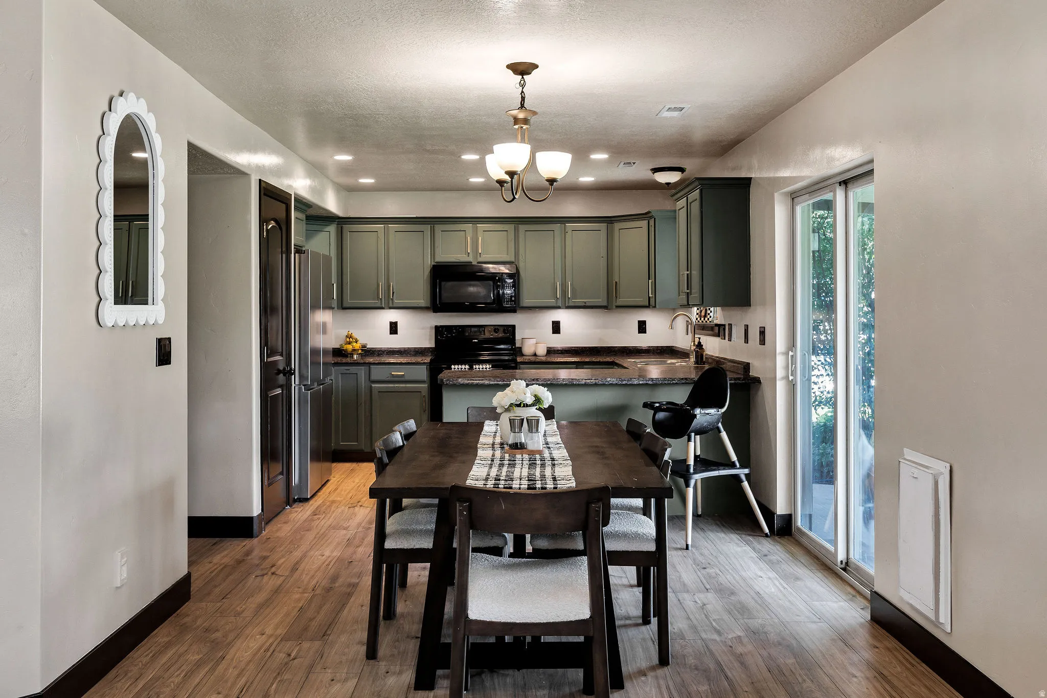Well-appointed kitchen featuring green cabinetry, dark countertops, and stainless steel appliances