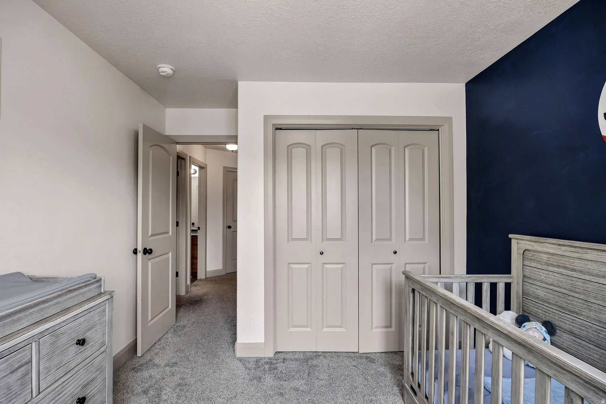 Neutral wall color, carpeted flooring, bi-fold closet doors, white interior doors, dark accent wall