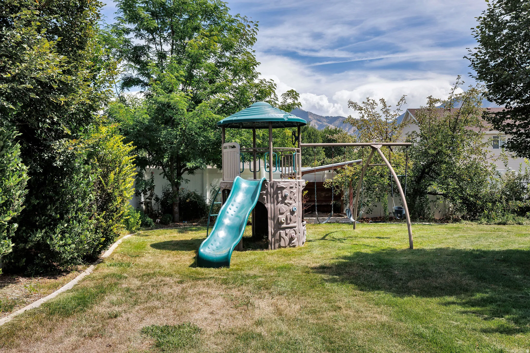 Expansive backyard featuring a lush lawn, mature perimeter landscaping, and a privacy fence