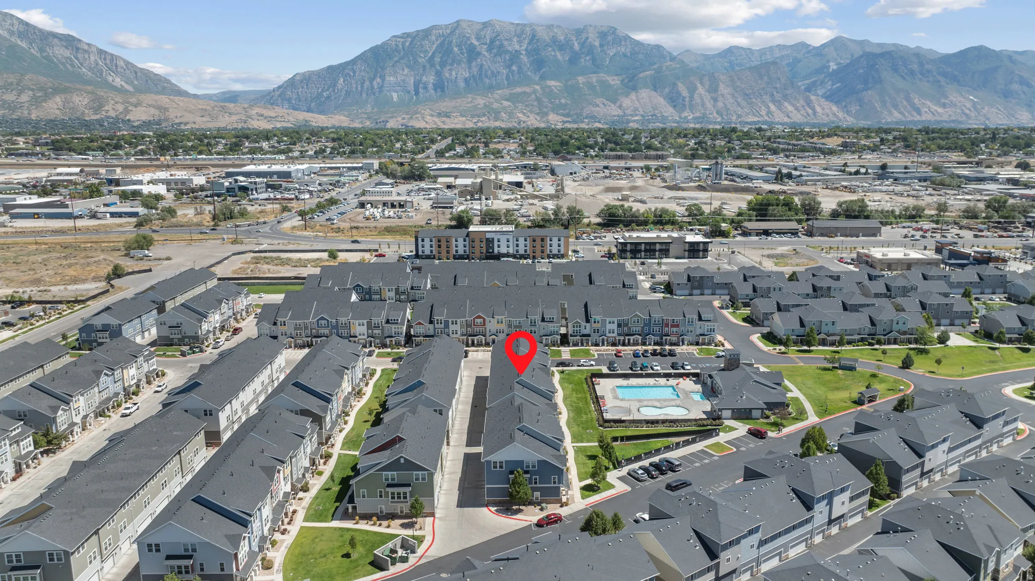 Community setting featuring a central swimming pool, paved parking areas, and manicured green spaces