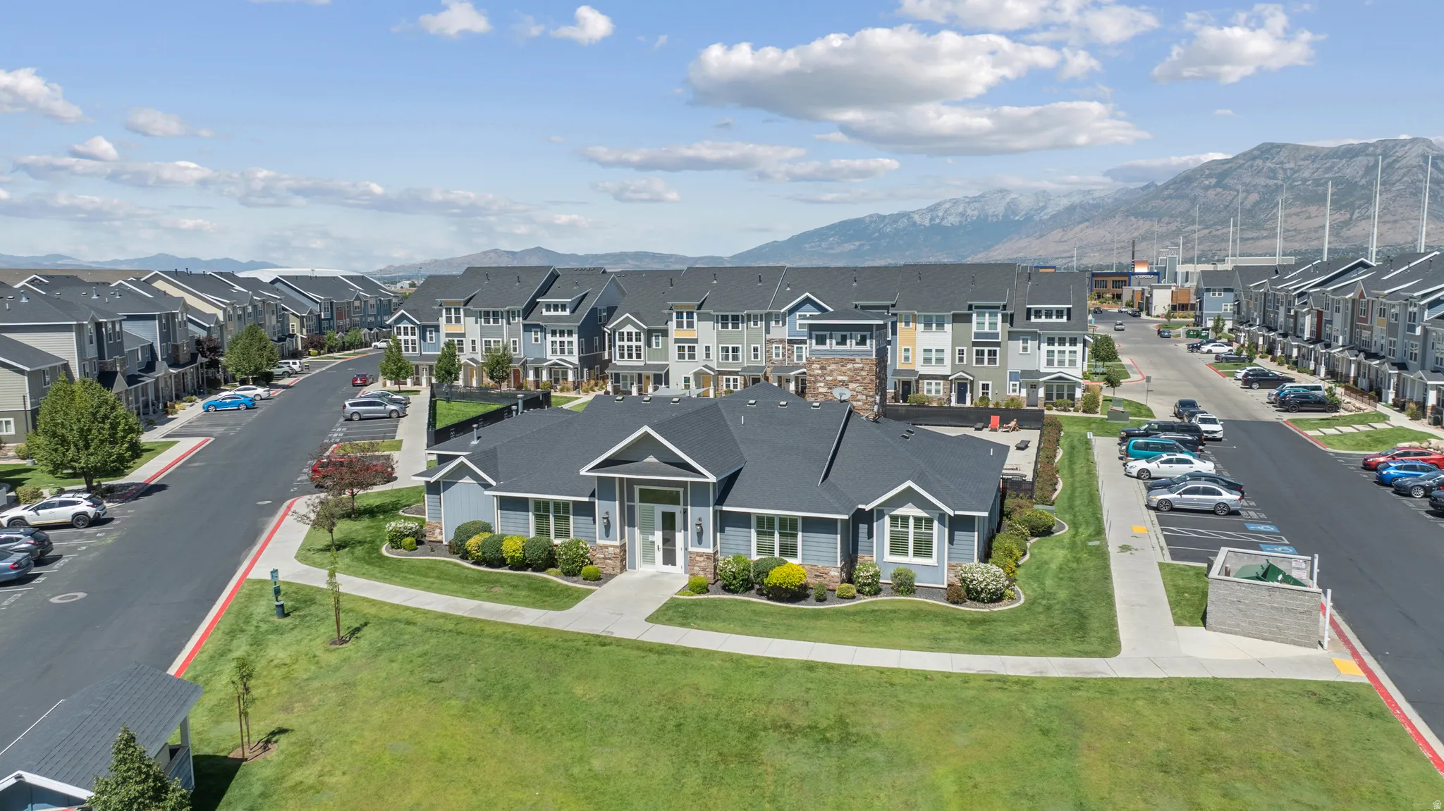 Community building with light blue siding and stone accents, surrounded by manicured lawns and paved walkways