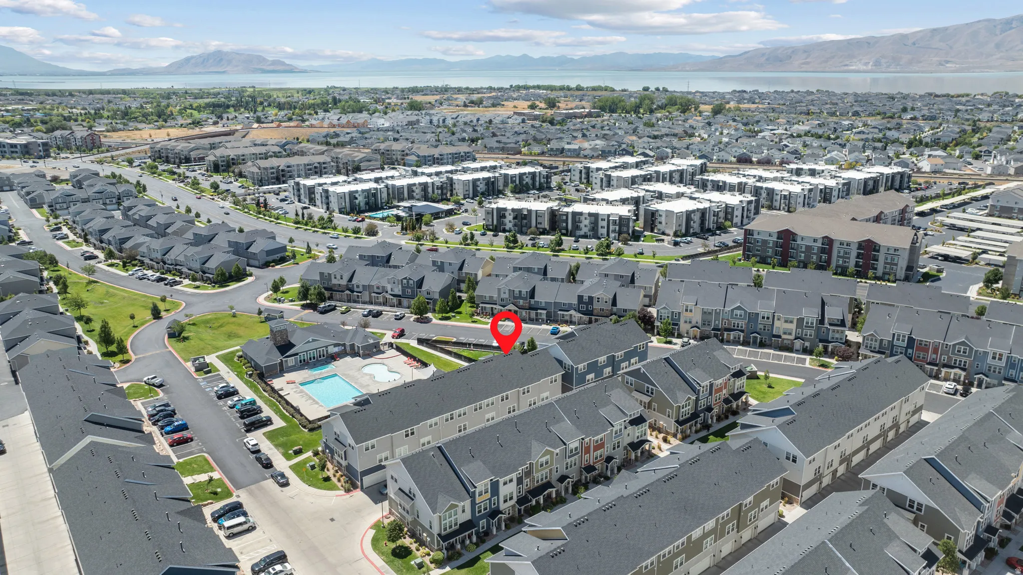 Aerial community overview featuring multi-story townhomes, structured street patterns, and a central pool area