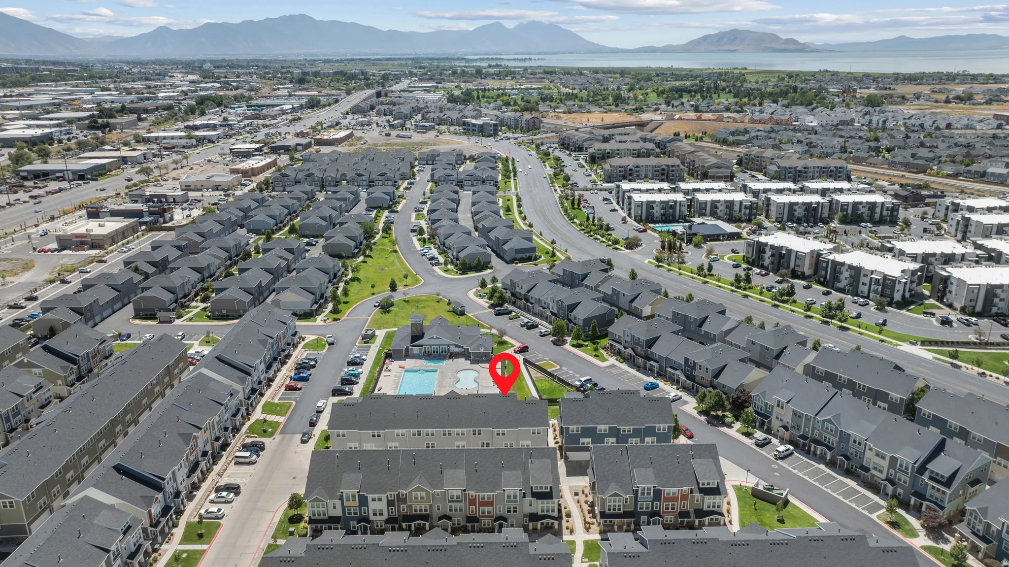 Aerial perspective showcasing a residential development with multiple buildings, a community pool, and surrounding infrastructure