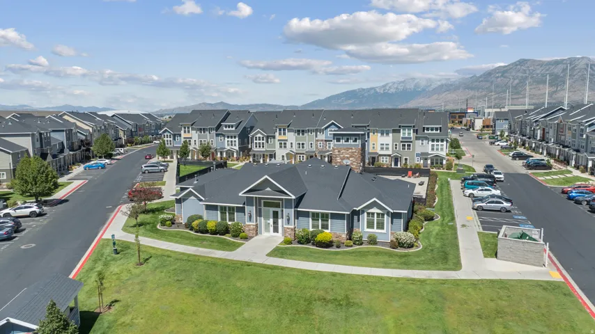 Community building with light blue siding and stone accents, surrounded by manicured lawns and paved walkways