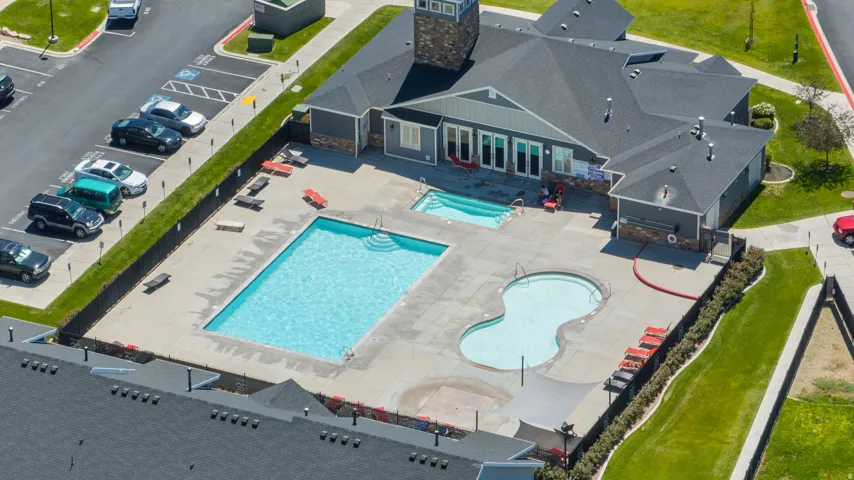 Outdoor aquatic facility featuring a rectangular swimming pool, a secondary freeform pool, and an in-ground spa