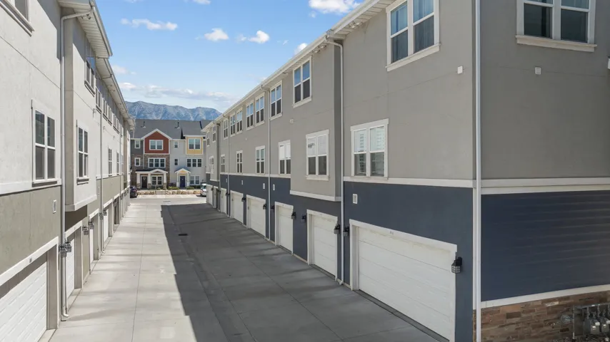 Multi-story townhomes featuring stucco and siding exteriors with attached garage doors, visible in a row