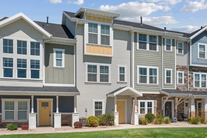Modern townhome exterior with varied siding, a covered entry, and a contrasting yellow front door