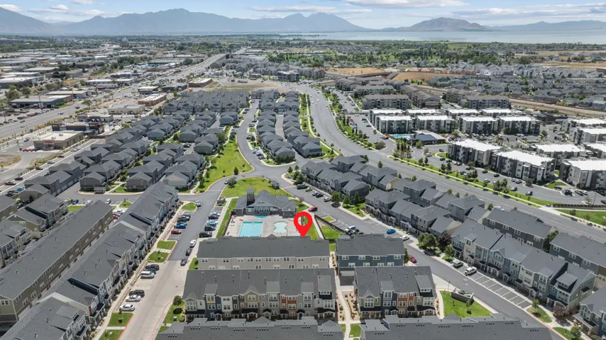 Aerial perspective showcasing a residential development with multiple buildings, a community pool, and surrounding infrastructure