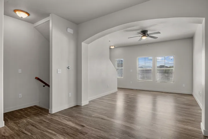 Wood-finish flooring throughout, arched entryway, and a ceiling fan with integrated lighting