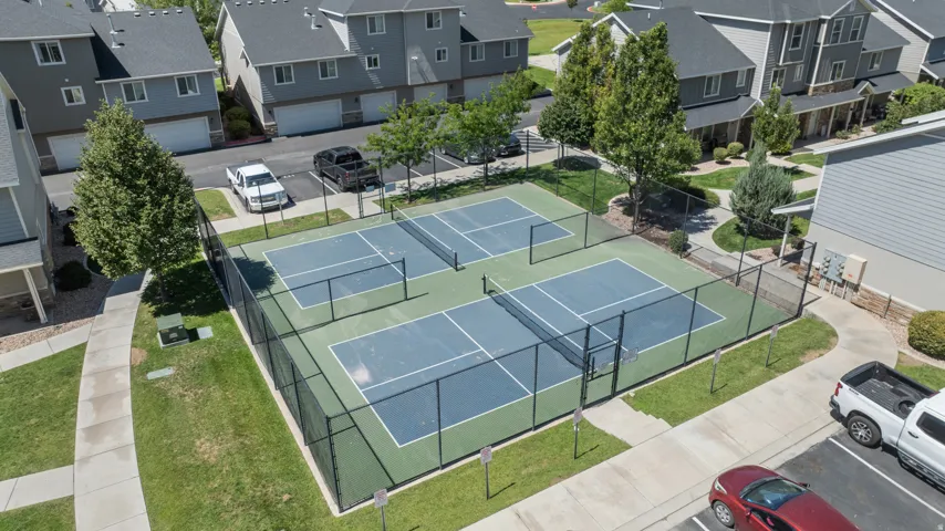 Four pickleball courts with perimeter fencing, surrounded by manicured green spaces and paved walkways