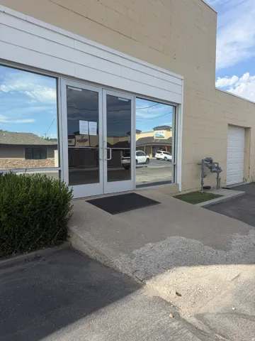 Storefront entrance featuring double glass doors, a concrete ramp, and a roll-up garage door