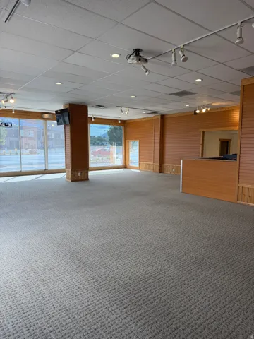 Expansive open-concept space featuring wall-to-wall carpeting and wood-finish paneling