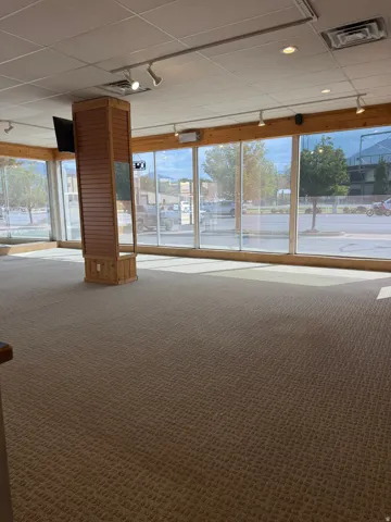 Expansive interior space featuring wall-to-wall carpeting and a decorative wood-paneled pillar