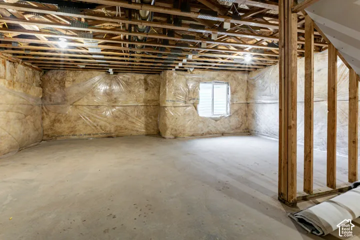 Unfinished lower level featuring exposed wood joists, concrete flooring, insulation-lined walls, and a single window