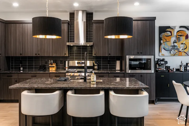 Spacious kitchen featuring dark wood-finish cabinetry, a large kitchen island with a dark stone countertop, and stainless steel appliances