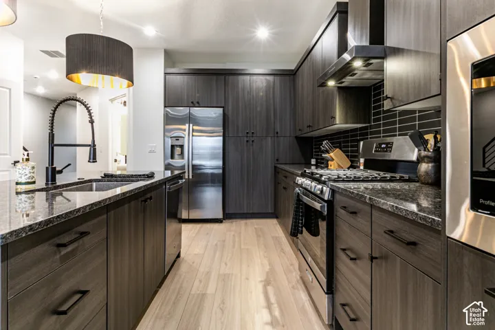 Modern kitchen featuring rich cabinetry, granite countertops, stainless steel appliances, a tile backsplash, and wood-finish flooring