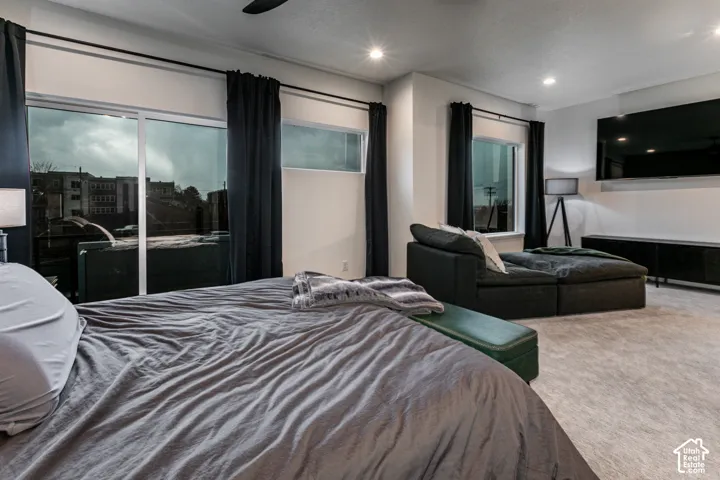 Sliding glass door to a private deck, recessed lighting, ceiling fan, and carpeted flooring