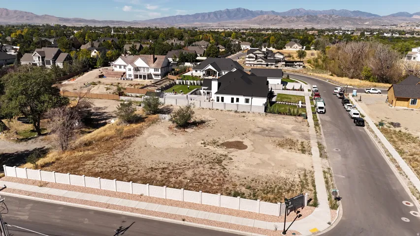 Expansive undeveloped lot with street frontage, bordering a residential neighborhood, and distant mountain backdrop