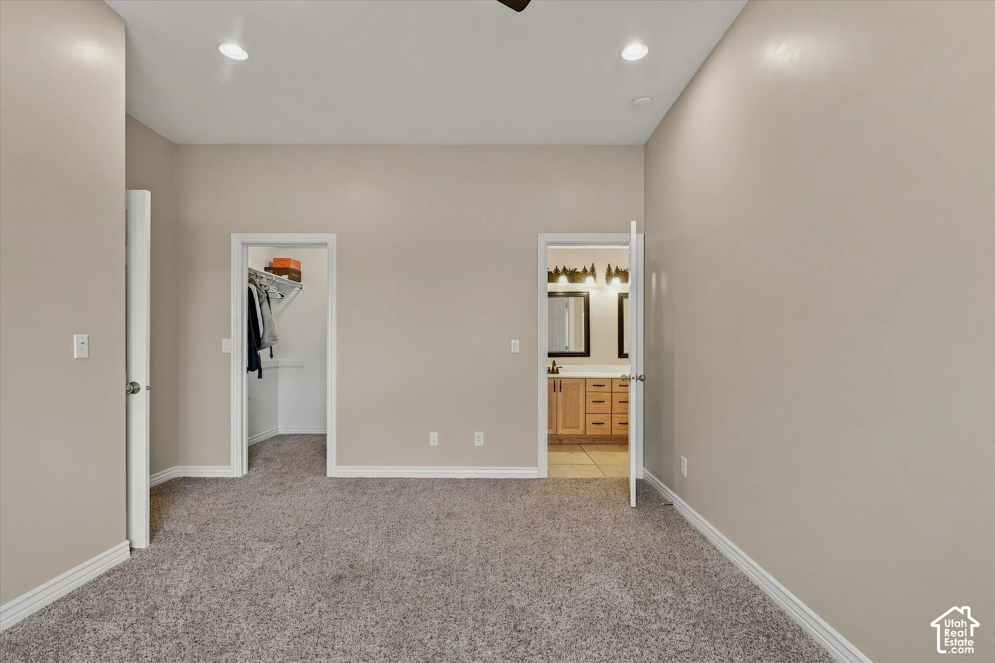 Recessed ceiling lighting, textured carpet flooring, walk-in closet, wood-finish vanity with dual sinks, and tile flooring in the bathroom