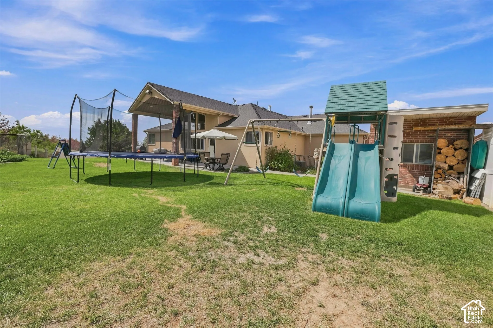 Expansive backyard with a covered patio, brick exterior, and a detached storage area