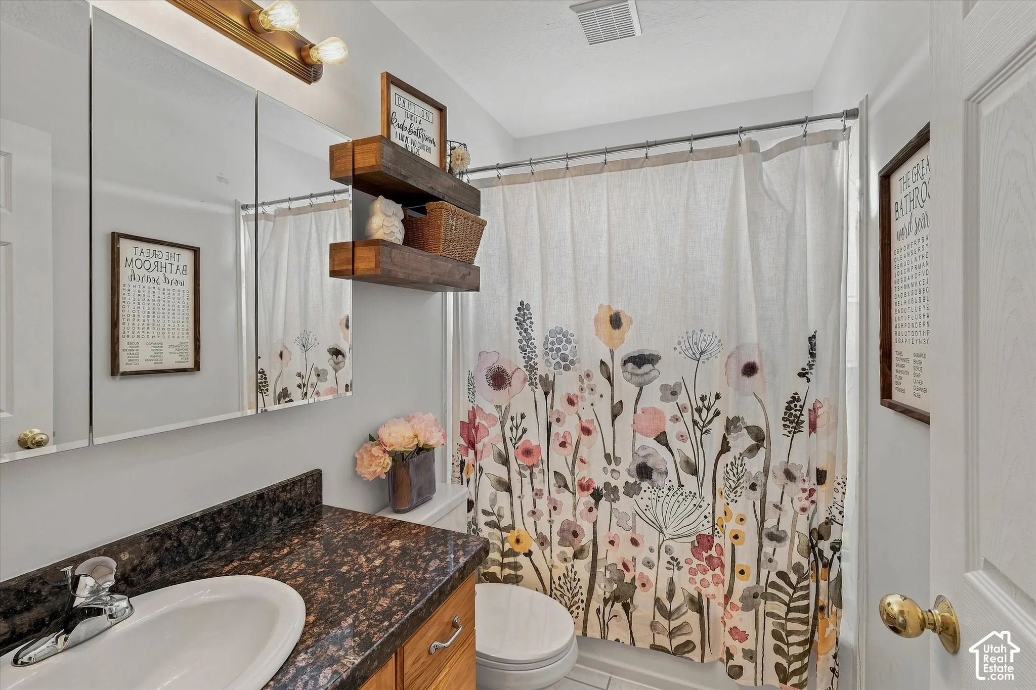 Bathroom featuring a single vanity with an integrated sink, dark speckled countertop, and a wood-finish cabinet
