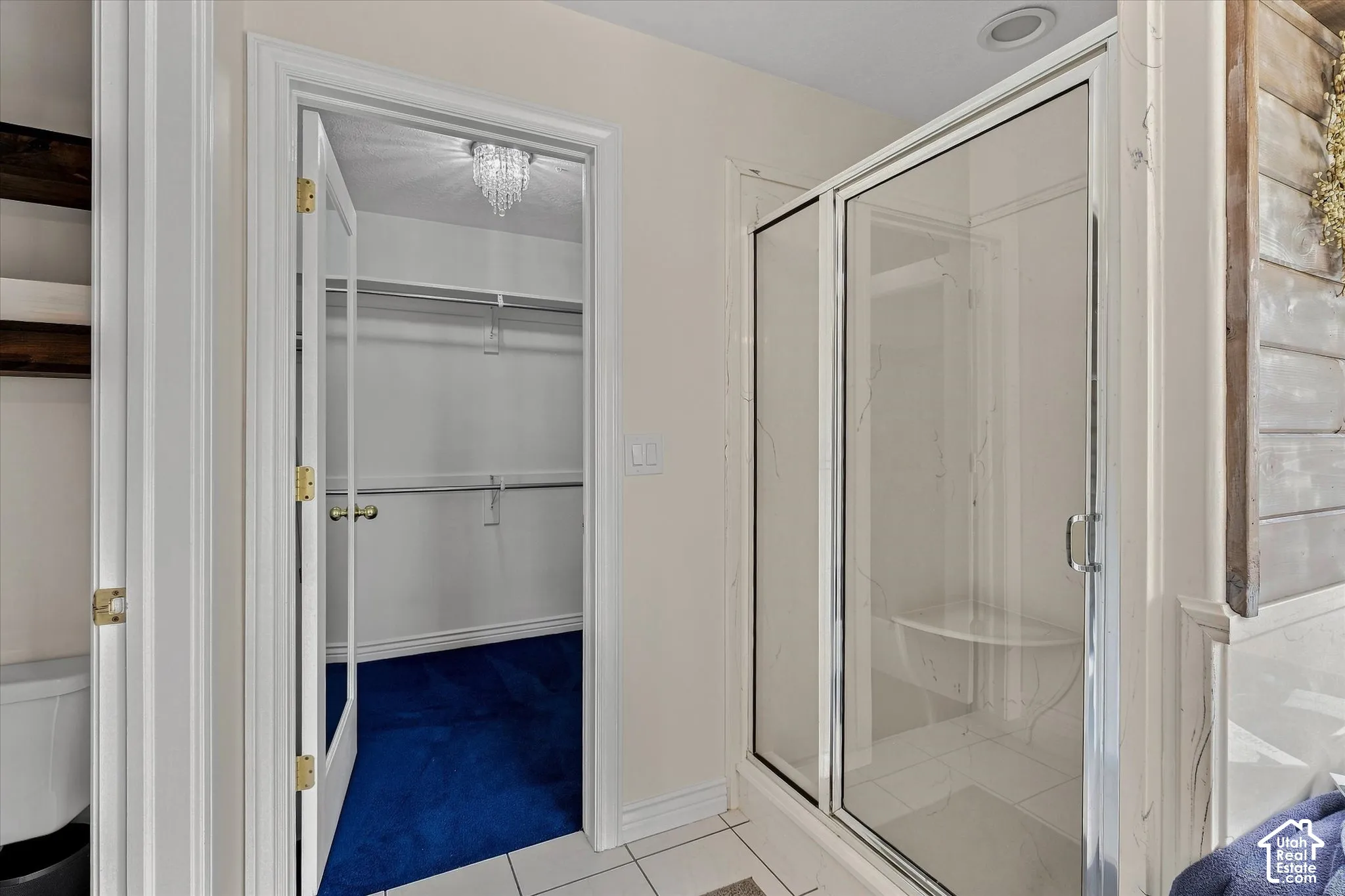 Glass-enclosed shower with integrated seating, tiled flooring, and a walk-in closet with built-in shelving