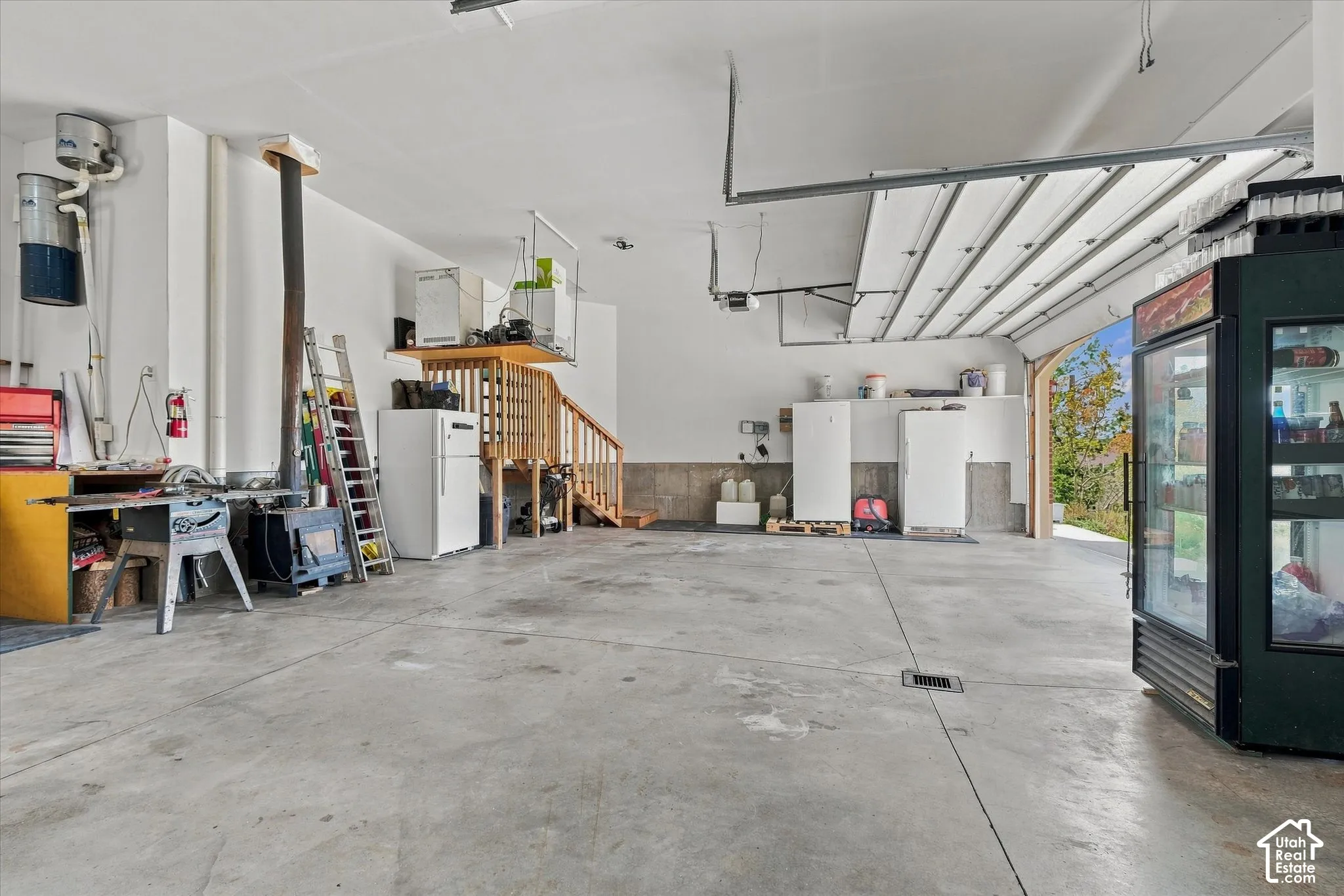 Spacious garage with a concrete floor, overhead garage door, and built-in wood staircase