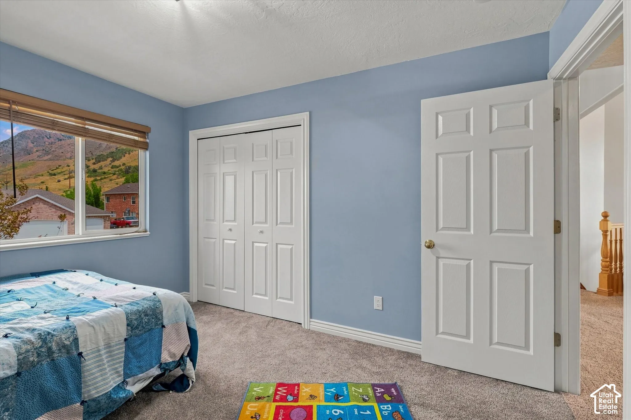 Plush carpeted flooring, a six-panel interior door, and a bifold closet door