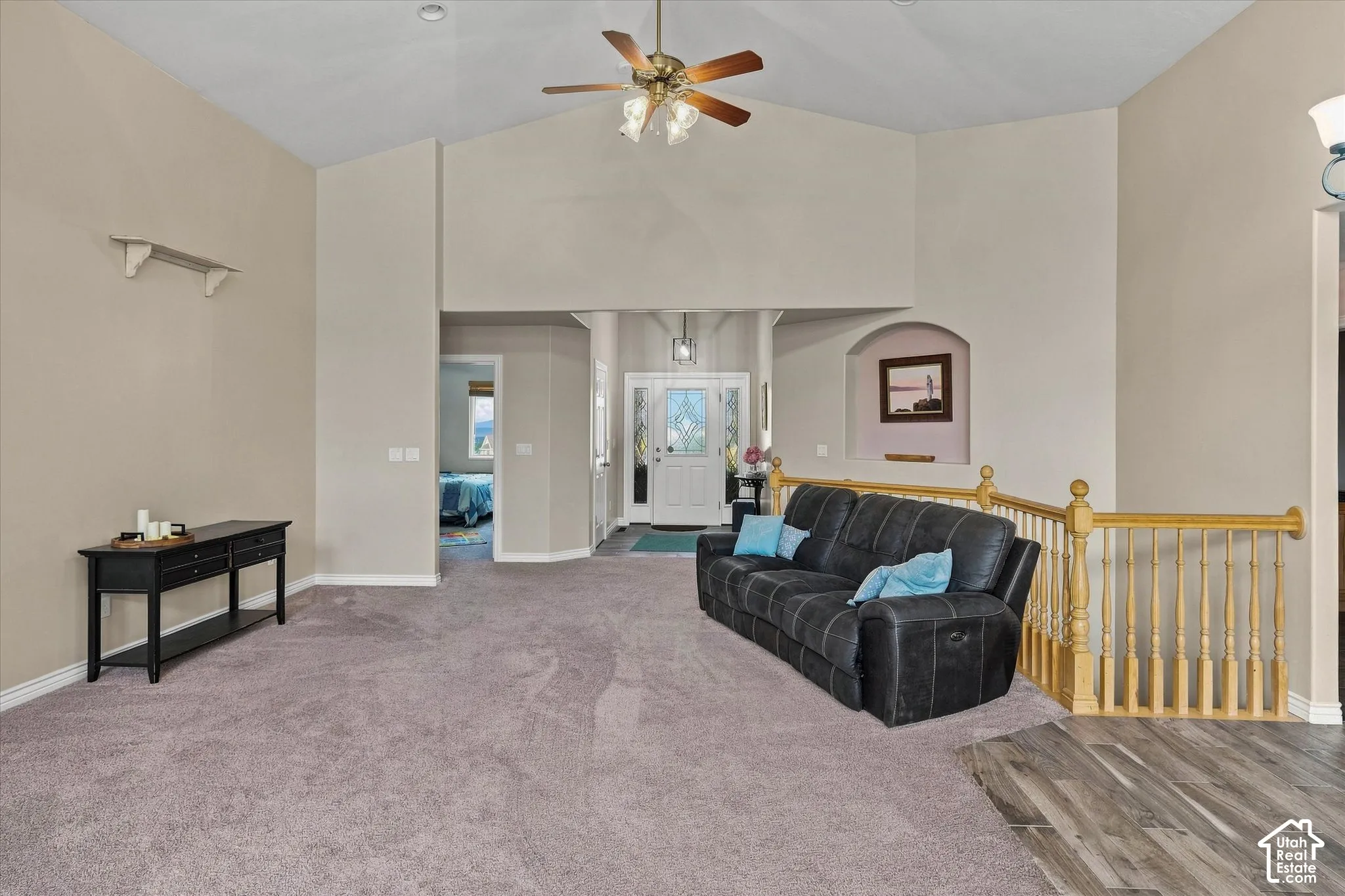 Vaulted ceilings with a ceiling fan, carpet flooring, archway, and wood-finish flooring
