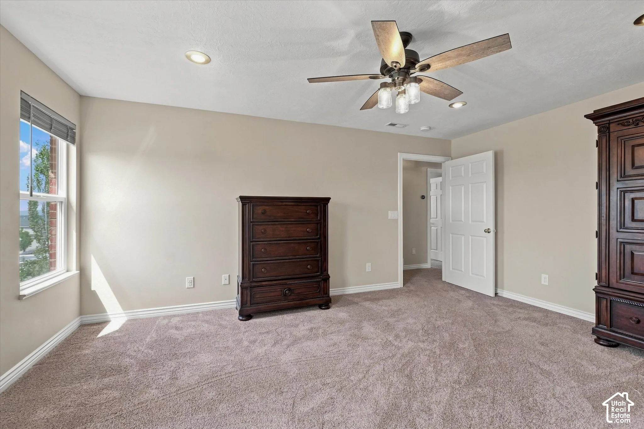Carpeted room featuring a ceiling fan with integrated lighting, recessed lighting, and a white paneled door
