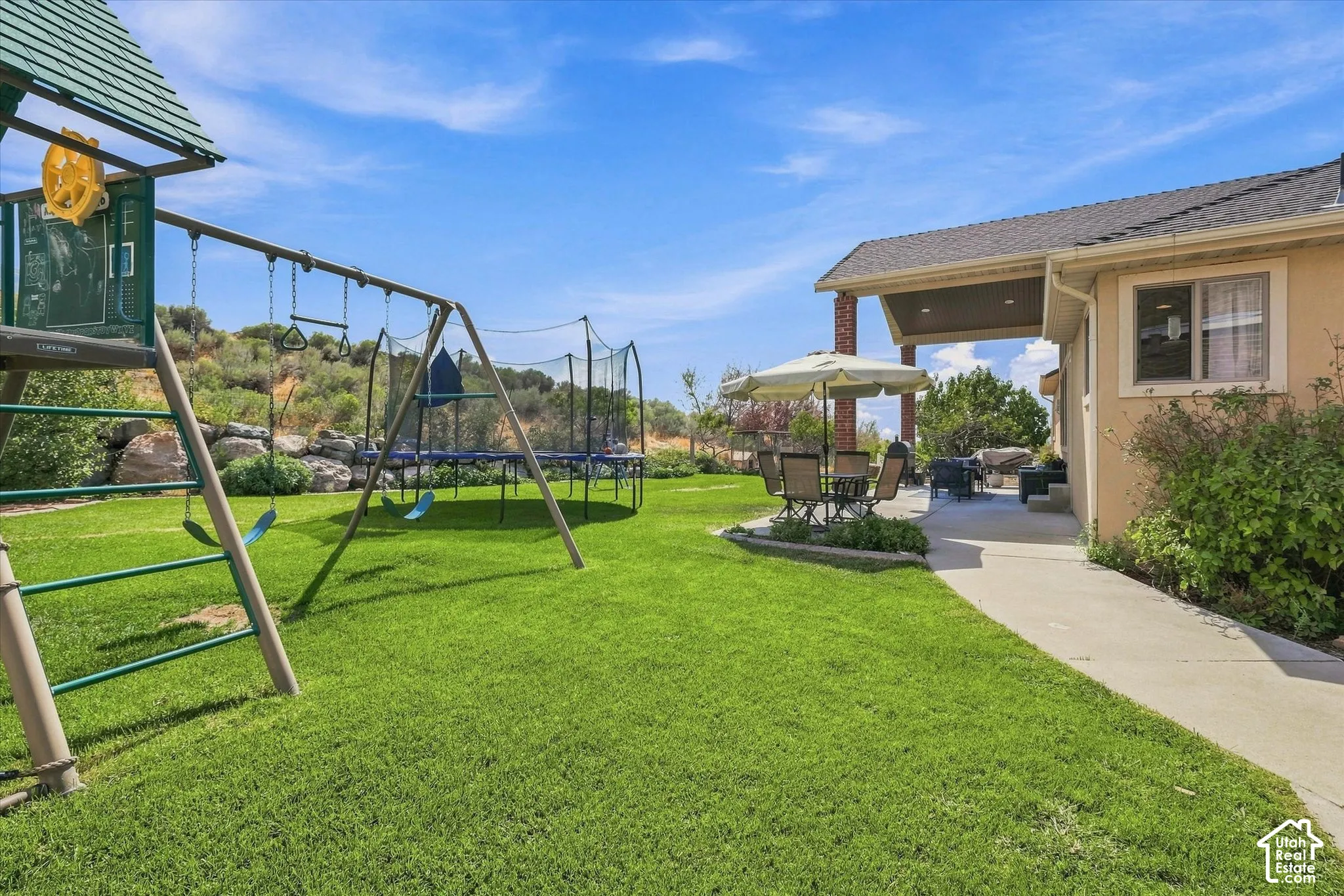 Expansive green lawn with a concrete pathway leading to a covered patio