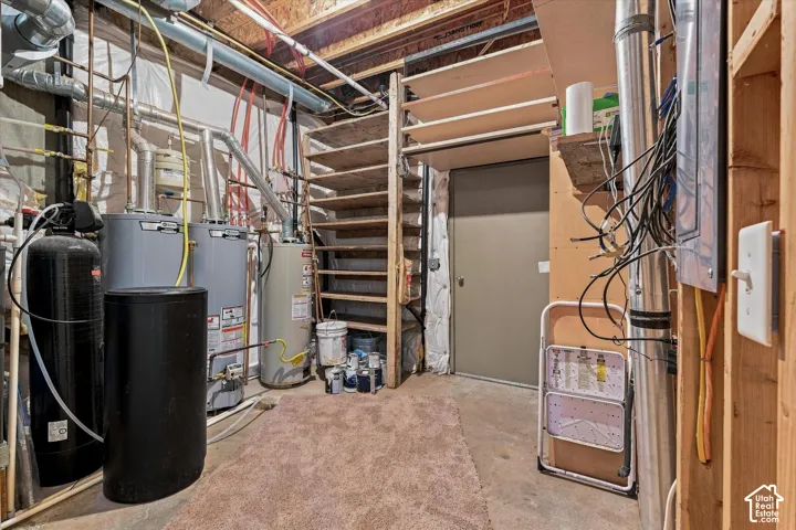 Utility area featuring multiple water heaters, a water softener, and built-in wood shelving